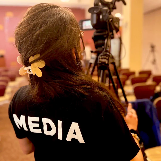 Media assistant filming with a camera.