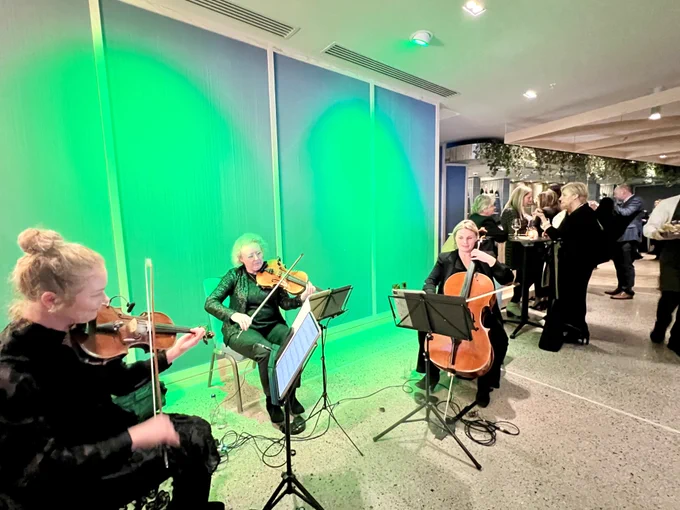 A trio of musicians playing at the CIE Awards of Excellence in Dublin, with award-goers chatting in the background. 