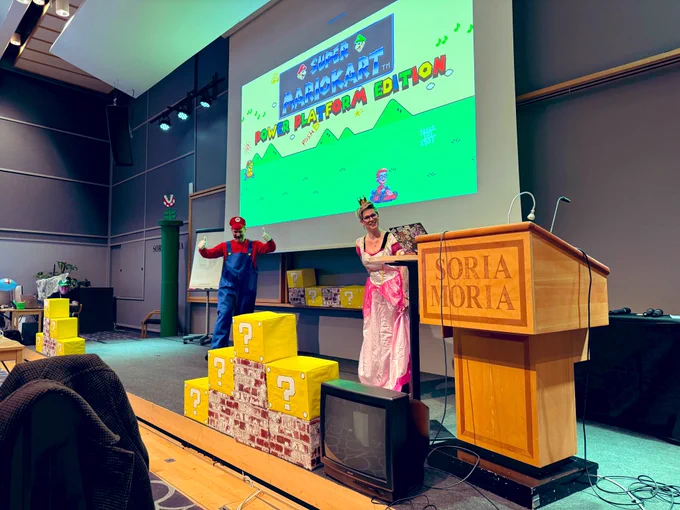 A stage decorated in a super Mario theme with Scott dressed as Mario and Sara as Princess Peach