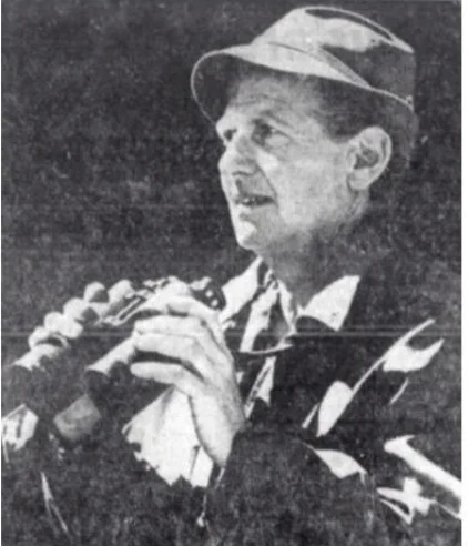 A black and white photo of Altmann holding binoculars, wearing field gear and a hat and looking throughful