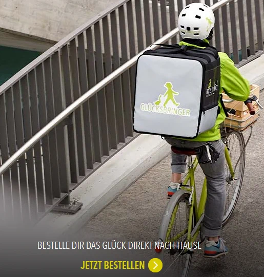 Werbung: Fahradkurier mit Rucksack, darauf "Hans im Glück"-Logo (Hans und Gans). Darunter: "BESTELLER DIR DAS GLÜCK DIREKT NACH HAUSE"