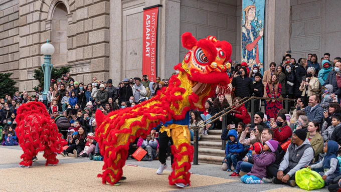 Two red lion dancers entertain crowds outside the National Museum of Asian Art.