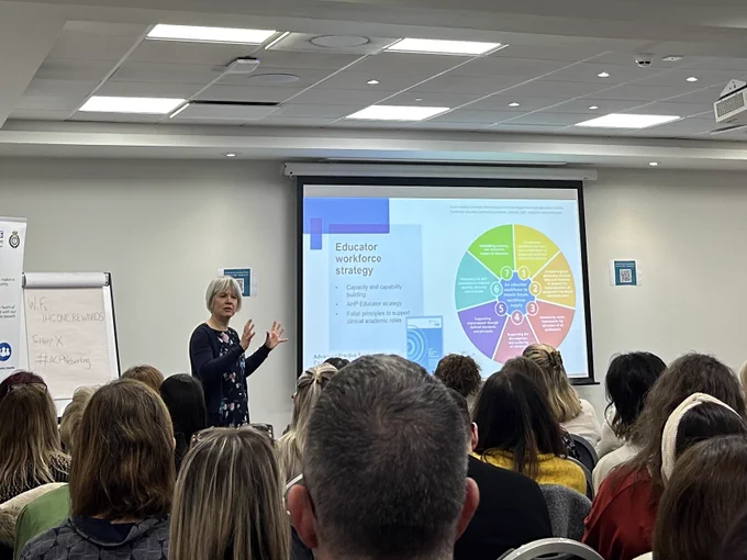 Beverly Harding presenting on the art of the possible in ACP. In the foreground of the photo, you can see the backs of the audiences heads