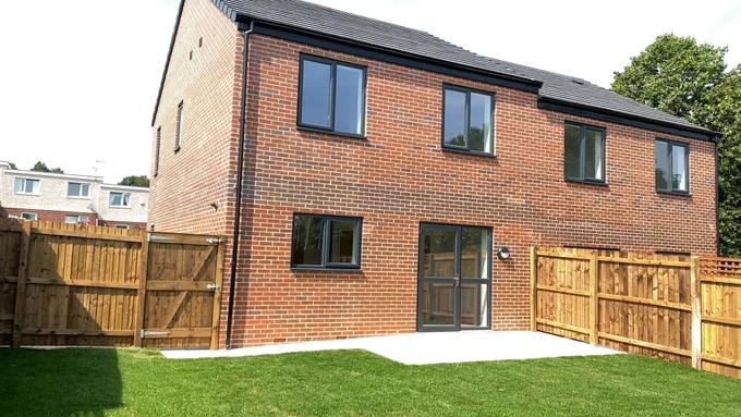 A red brick semi detached new build with fenced back gardens and a patio area with patio doors leading to the back garden