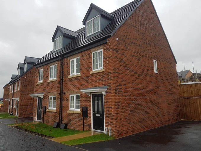 A row of red brick new builds with neat front gardens and tarmac drives 
