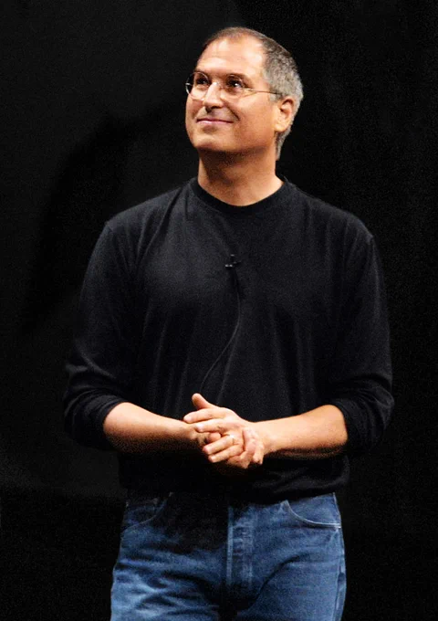 A portrait of Steve smiling in glasses and a black turtleneck from 2001.