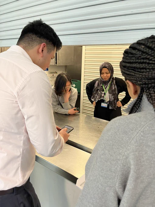 A group of people spinning a coin on a metallic kitchen surface