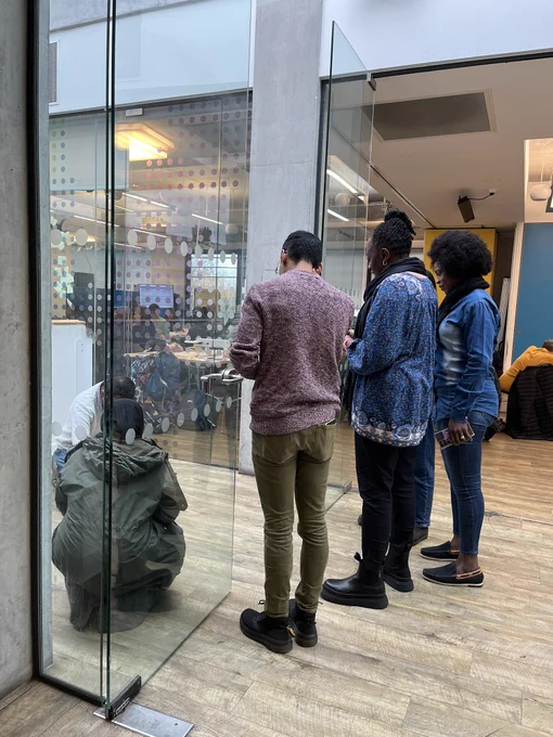 A group of people spinning a coin on the floor between doors