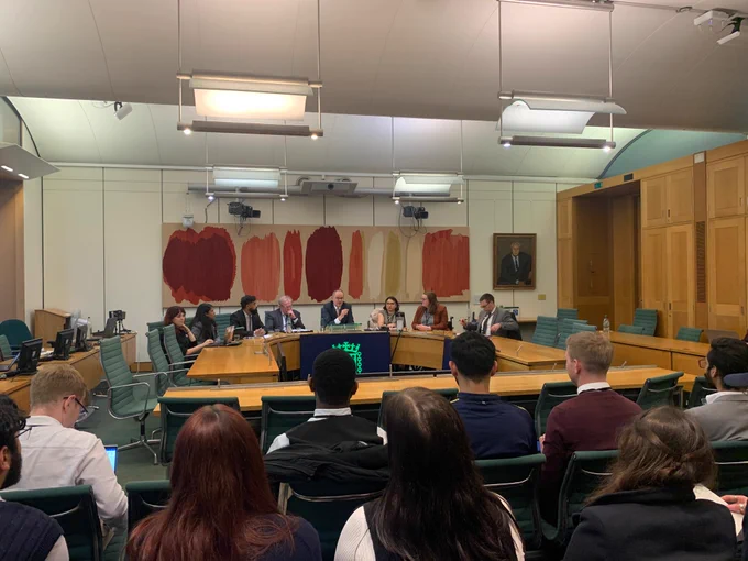 a group of panel members sat in front of an audience of students in UK Parliament