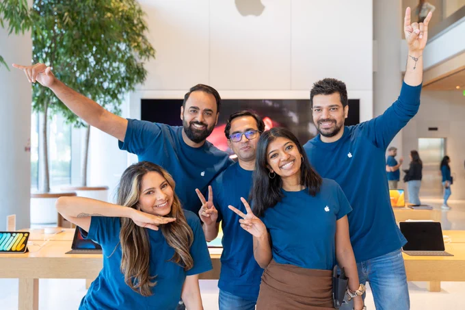 Five Apple retail employees smiling and posing together at Apple BKC.