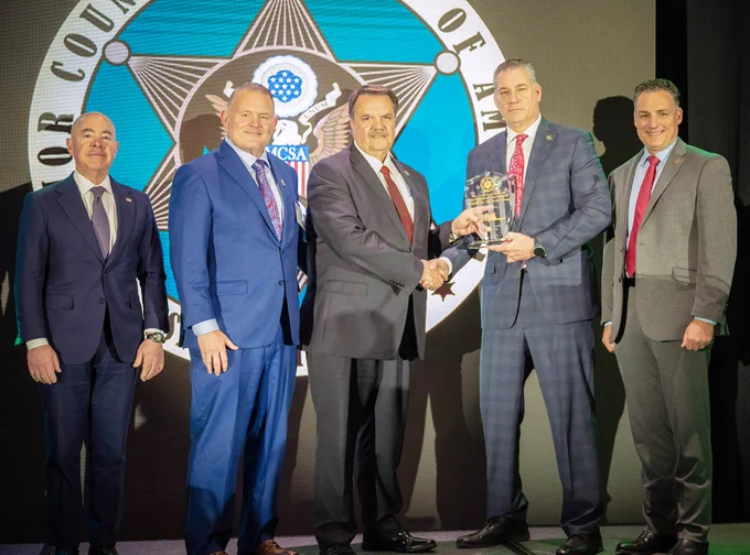 Middlesex Sheriff Peter J. Koutoujian shakes the hand of Major County Sheriffs of America President, Bill Brown, as he accepts the Sheriff of the Year Award with Secretary of Homeland Security Alejandro Mayorkas, Motorola Solutions Vice President Frank Galvin and MCSA Immediate Past President Dennis Lemma.