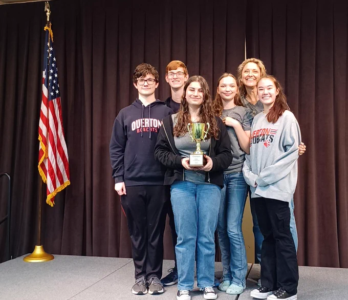 Overton High School student, holding the Battle of the Books 2024 trophy.