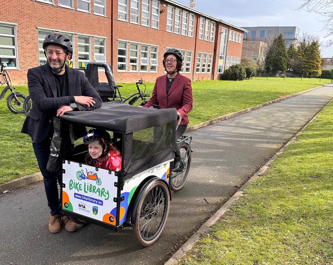 Two adults and a child on a family-friendly cargo bike