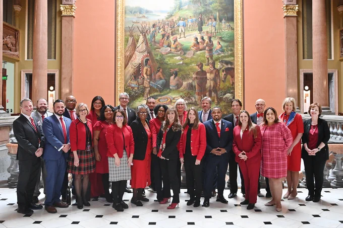A group of senators wearing red pose for a photo inside the Illinois State Capitol.
