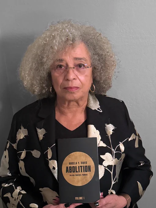 Angela Davis holds up a copy of her new book Abolition: Politics, Practices, Promises Vol. 1