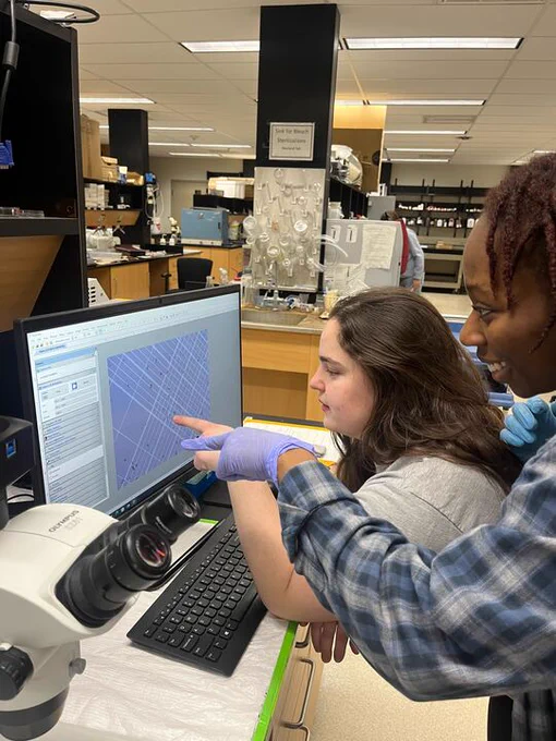 Two students looking at algae under a hemocytometer.