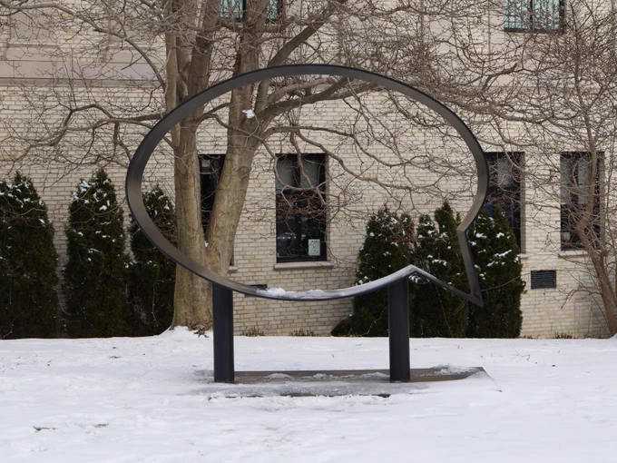 A sculpture of a speech bubble on the MAM grounds standing tall amongst a patch of snow.