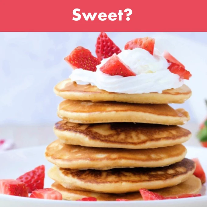 A tower of American style pancakes topped with whipped cream and strawberries. A banner at the top reads 'Sweet?'