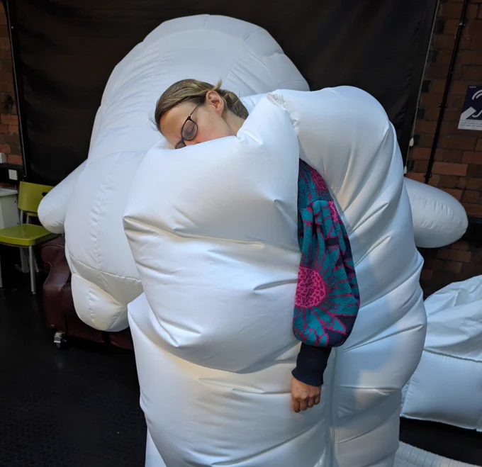 A relaxed person engulfed by a white inflatable robot.