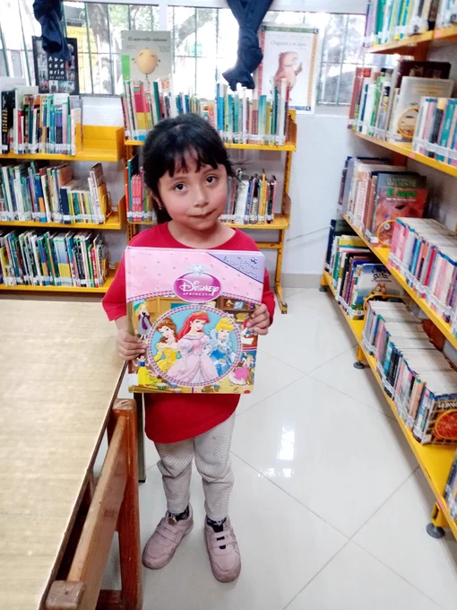A little girl holding a book in a library