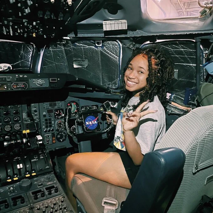 Kyndall Jones, a former NASA JPL intern and student at Howard University, 
sits in a cockpit at NASA's Armstrong Flight Research Center. She smiles and makes a peace sign.  

Credit: NASA JPL/Kyndall Jones