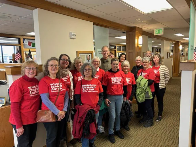 Rep Andersen outside his office with over a dozen Moms Demand Action representatives wearing red shirts with the Moms Demand Action logo