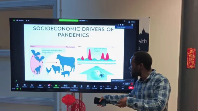 Researcher presenting at a screen on the socioeconomic drivers of pandemics.