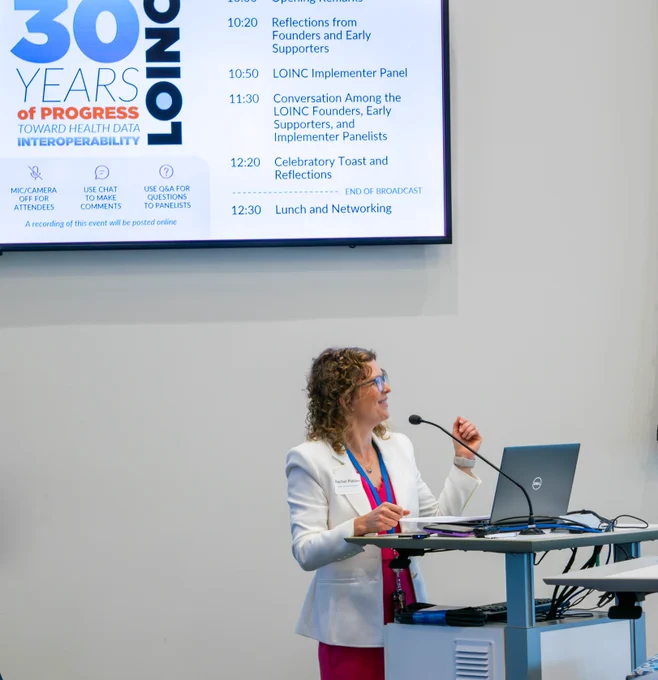 Rachel Patzer, PhD, President and CEO of Regenstrief Institute stands at a podium giving welcoming remarks to the event. 