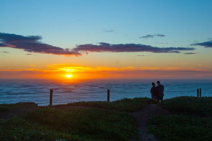 Two people watch the sun set at Point Bonita.