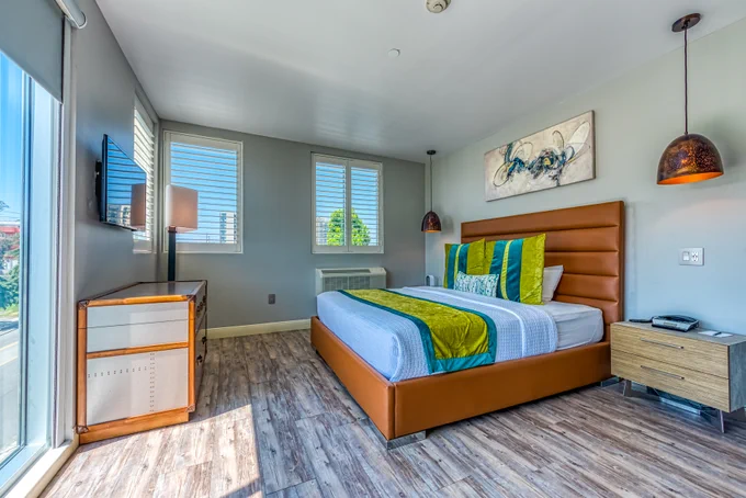 Lexen Hotel room in North Hollywood with chic retro furniture: bed, dresser, night stand, pendant lights, bright throw pillows and bed throw. 