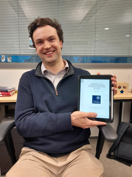 Me holding an iPad with the front cover of my DPhil thesis.