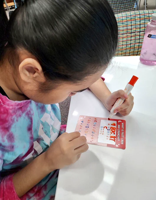 Girl using marker to decode joke activity sheet