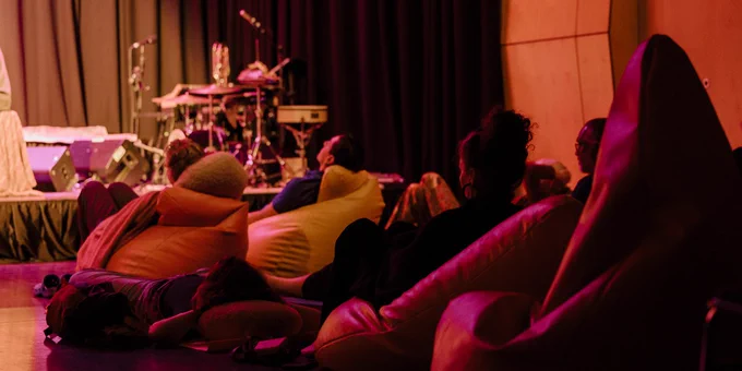 People lounging on beanbags while watching a performance ons tage,