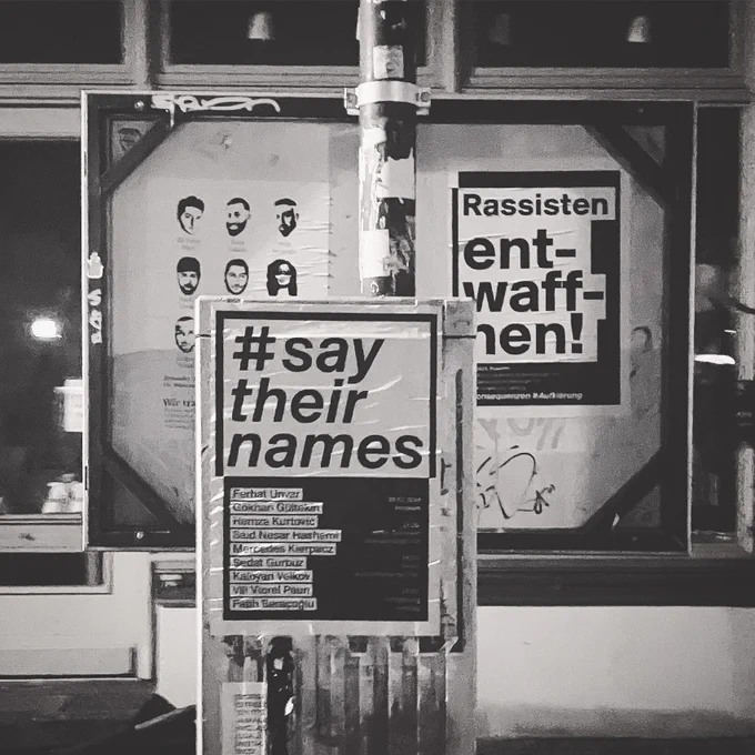 an einer haltestelle kleben 3 plakate anlässlich des jahrestages des rechtsextremistischen anschlages von hanau. 

1 plakat zeigt die gesichter und namen von Gökhan Gültekin, Sedat Gürbüz, Said Nesar Hashemi, Mercedes Kierpacz, Hamza Kurtović, Vili Viorel Păun, Fatih Saraçoğlu, Ferhat Unvar und Kaloyan Velkov

auf dem zweiten plakat steht groß:
#say
their
names

darunter die namen der opfer des anschlags. 

auf dem dritten plakat steht groß: Rassisten entwaffnen!