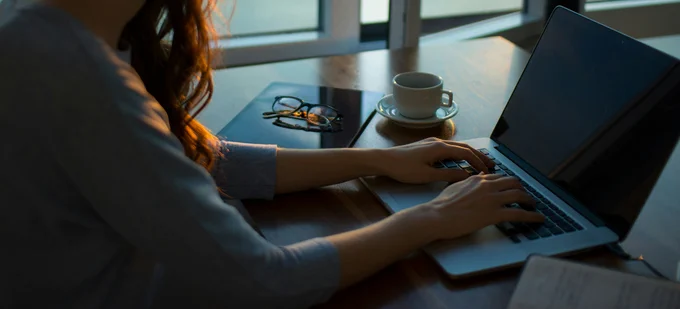 A person sits at a desk typing at a laptop