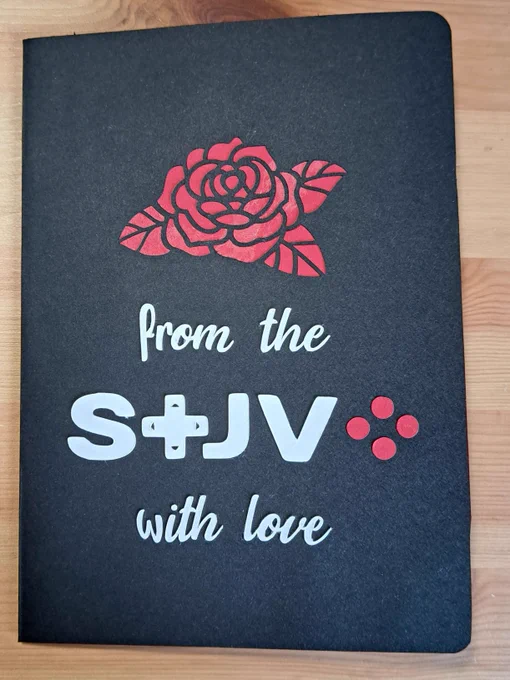 Une carte de saint valentin fermée faite à la main, fond noir avec une rose rouge et le texte : from the STJV with love.