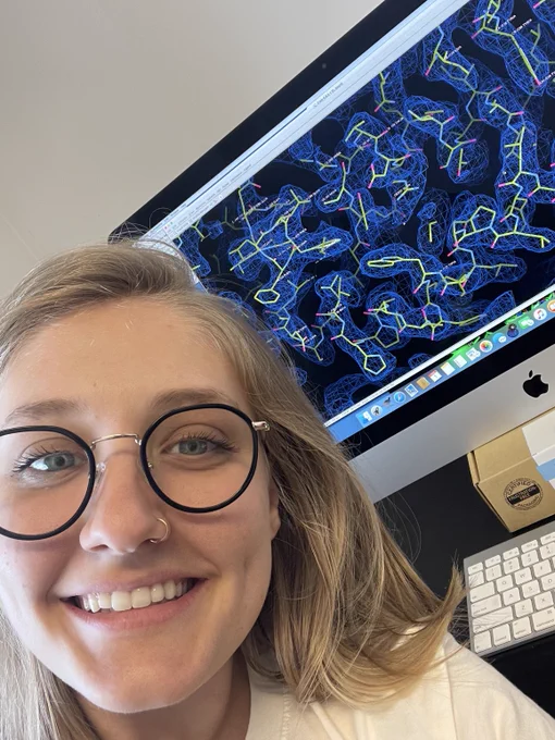 Jacqueline Ehrlich smiling in front of an Apple desktop displaying images of her research.