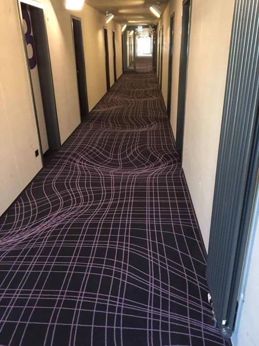 Hotelflur mit Teppich dessen Muster eine Hügellandschaft optisch vortäuscht