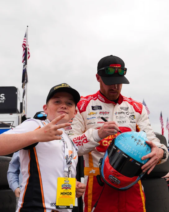 A fan gives the peace sign while Jeb Burton signs his helmet.