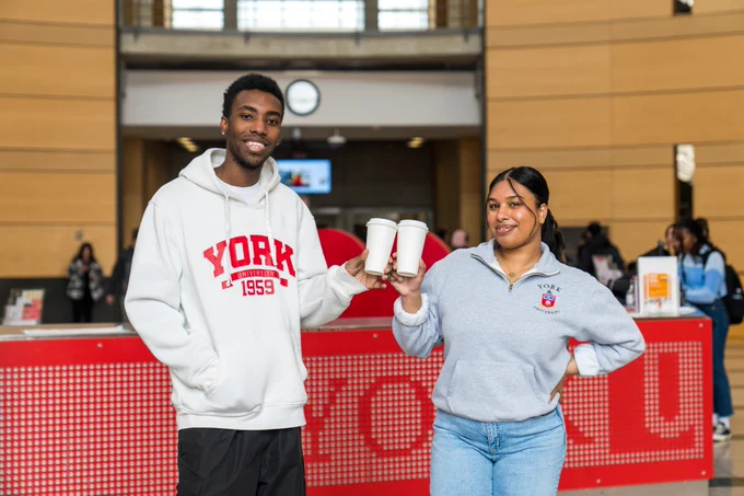 Two students clinking coffee cups together