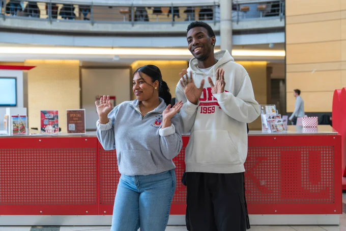 Two students waving