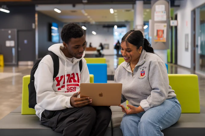 Two students looking at a laptop