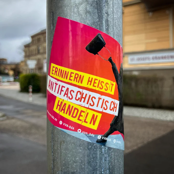 sticker an pfeiler: ein foto der statue „The Woman With the Handbag" die danuta danielsson zeigt, eine frau die einen neonazi mit ihrer handtasche angegriffen hat, dazu steht:
erinnern heißt antifaschistisch handeln.
