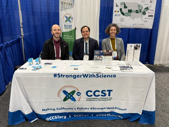 People sitting at a conference booth table.