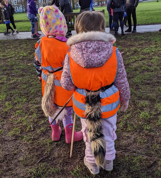 Two junior parkrunners with fluffy tails, taking part in their tail walker role.