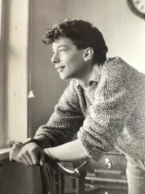 A black and white photo of me at 17. I’m leaning over a chair wearing a baggy grey jumper. My hair is awesome.