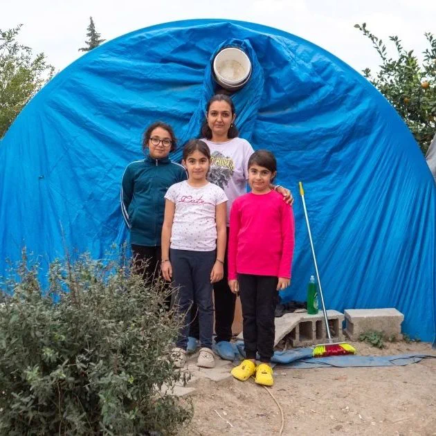 Erva and her three daughters pose to the picture in front of their tent.