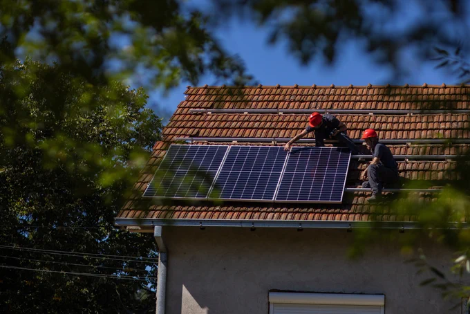 engineers are installing solar panels on the roof of a home