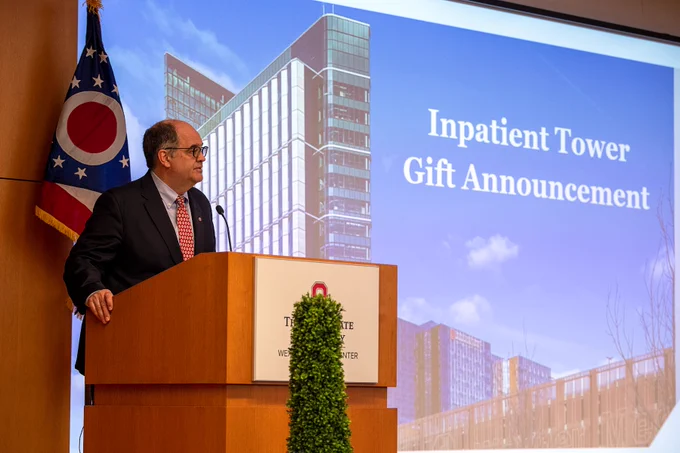 Man standing behind podium in front of screen.