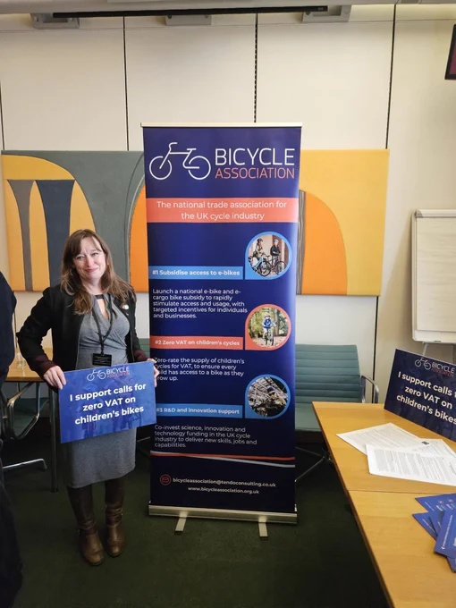 Emily standing with a banner sign calling for no VAT on Childrens Cycles 